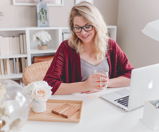 A woman drinks tea at her computer